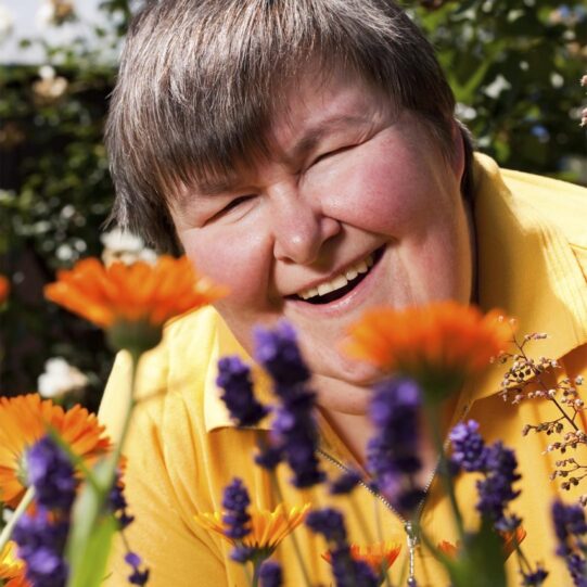 mentally disabled woman is in the garden and smell of flowers - Intermediate Care Facilities Consulting